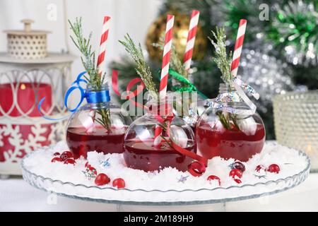 Gin mit Tonic und Preiselbeersaft. Der Cocktail ist voller festlicher Weihnachtsaromen. Serviert in transparenten Schüsseln mit einem Zweig Rosmarin. Stockfoto