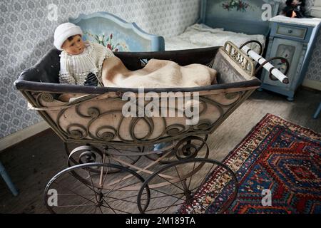 Antiker Kinderwagen mit Babypuppe im alten Schlafzimmer Stockfoto