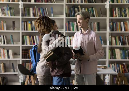 Freute, glückliche Studenten, die sich in der öffentlichen Bibliothek umarmen Stockfoto