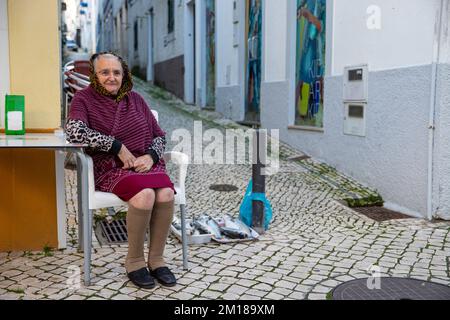 Nazare, Portugal - 09.12.2022: Ältere Dame verkauft rohen Fisch Stockfoto