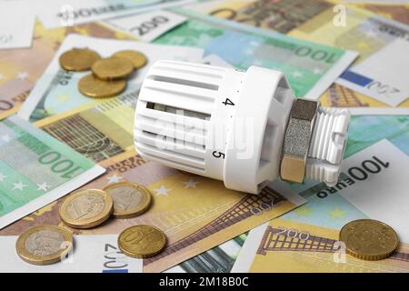 Thermostatischer Ventilkopf auf Euro-Banknoten-Hintergrund. Steigender Verbrauch. Konzept der Stromkosten und teurer Energie. Preiserhöhung. Heizung Cr Stockfoto