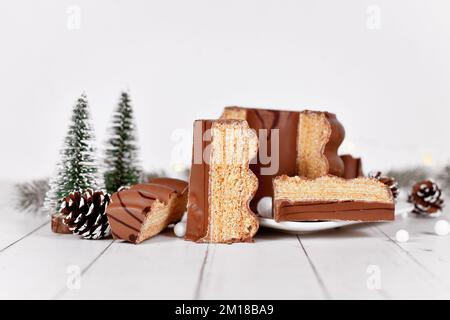 Schneiden Sie den traditionellen, mit Schokolade verglasten, geschichteten Winterkuchen „Baumkuchen“ vor der saisonalen Dekoration auf Stockfoto