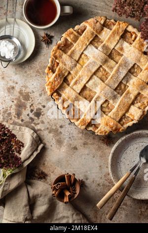 Hausgemachter Apfelkuchen, Tischszene von oben auf braunem strukturiertem Hintergrund. Flach verlegt Stockfoto