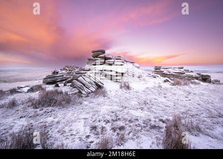 Merrivale, Dartmoor-Nationalpark, Devon, Großbritannien. 11.. Dezember 2022. UK Weather: Fire and Ice on Dartmoor. Der Himmel bei Sonnenaufgang leuchtet orange auf dem schneebedeckten Great Mis Tor an einem kalten und winterlichen Morgen. Die Winterbedingungen werden sich diese Woche mit weiteren Schneeprognosen fortsetzen. Kredit: Celia McMahon/Alamy Live News Stockfoto