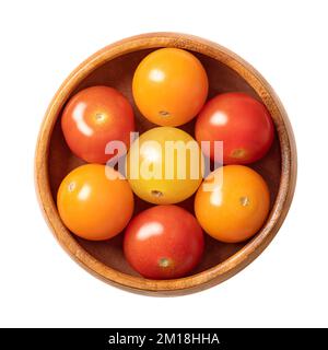 Bunte Kirschtomaten in einer Holzschüssel. Frische und reife kleine und runde Cocktailtomaten in Rot, Gelb und Orange. Stockfoto