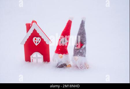 Süße Zwerge mit rotem Hut und roter Hausfigur. Dekoratives Weihnachtsspielzeug. Stockfoto