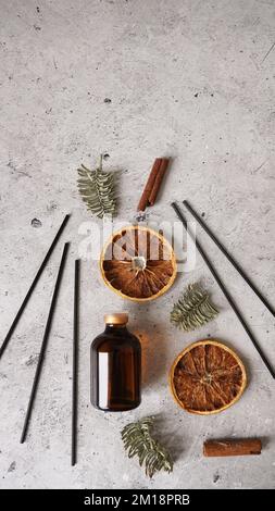 Zitrusrebendiffusor mit Zimt, trockenen Orangen- und Tannenbaumen. Parfum für Zuhause. Trendkonzept, natürliche Materialien. Vertikales Foto Stockfoto