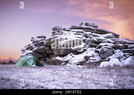 Merrivale, Dartmoor-Nationalpark, Devon, Großbritannien. 11.. Dezember 2022. UK Weather: Fire and Ice on Dartmoor. Das einsame Zelt eines tapferen „wilden Campers“, der am Fuße eines schneebedeckten Great Mis Tor ein Camp aufgebaut hat. Die Winterbedingungen werden sich diese Woche mit weiteren Schneeprognosen fortsetzen. Kredit: Celia McMahon/Alamy Live News Stockfoto