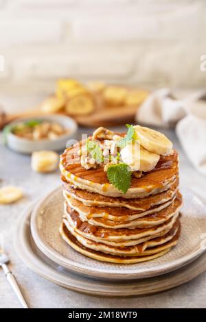 Zum Feiern des Pfannkuchen-Tages, amerikanisches hausgemachtes Frühstück. Glutenfreie Bananen-Pfannkuchen mit Nüssen und Karamell auf einer Tischplatte aus Stein. Speicherplatz kopieren. Stockfoto