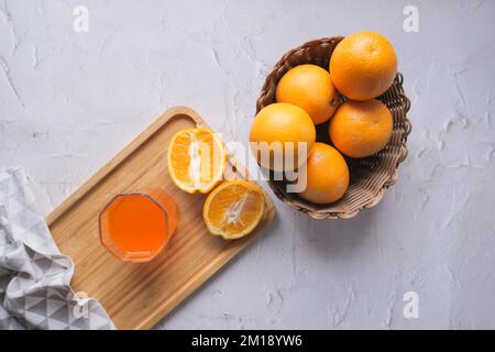 Orangensaft im Glas und Obst in einer Schüssel auf dem Tisch Stockfoto