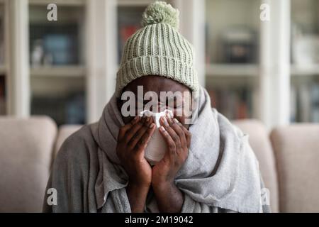 Die Verhaftung eines kranken afroamerikanischen Mannes, der von einer Decke bedeckt war, die niesen musste Stockfoto