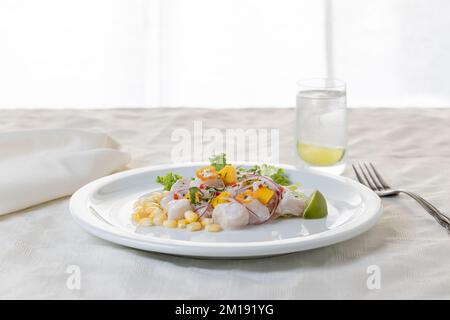 Ceviche, typisches Fischgericht der peruanischen Küche auf einem Tisch mit weißer Tischdecke. Stockfoto