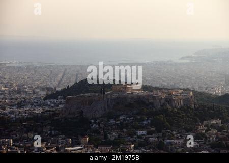 Ein Blick aus der Vogelperspektive auf die Akropolis auf einem Hügel vor dem Meer in Athen, Griechenland Stockfoto