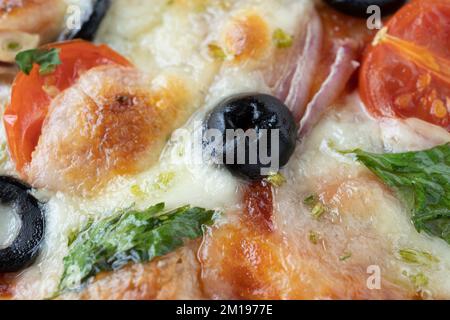Makroaufnahme von italienischer Pizza mit Mozzarella und Kirschtomaten, Pilzen und roten Zwiebeln, Gewürzen, Ketchup und Paprika. Italienische Küche. Stockfoto