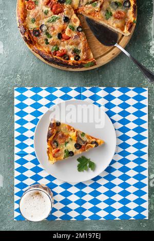 Oktoberfest: Bier- und Essensfestival, Bier und Pizza auf weiß-blauer Tischdecke Stockfoto