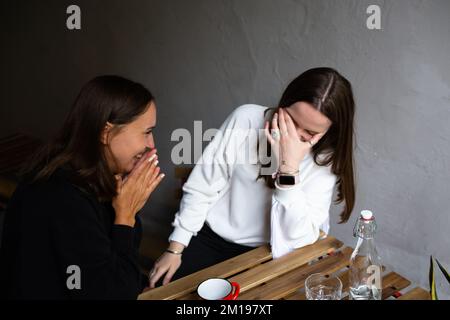 Zwei junge Freundinnen kommunizieren und haben Spaß in einem Straßencafé Stockfoto