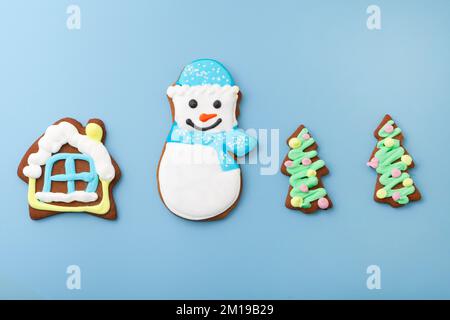 Lebkuchen-Schneemann-Blick und Haus mit weihnachtsbaum. Verschiedene Kekse auf blauem Hintergrund Stockfoto