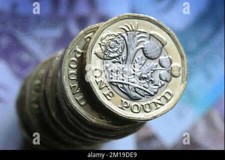 EIN HAUFEN BRITISCHER 1-PFUND-MÜNZEN AUF BRITISCHEN BANKNOTEN ÜBER DIE WIRTSCHAFTLICHE REZESSION INFLATION GELDAUSGABEN ETC. UK Stockfoto