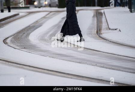 Rostock, Deutschland. 11.. Dezember 2022. Eine Frau geht über eine schneebedeckte Kreuzung im Stadtzentrum. Aufgrund von Schneefall und rutschigen Straßen gibt es in Norddeutschland Verkehrsbehinderungen. Kredit: Frank Hormann/dpa/Alamy Live News Stockfoto