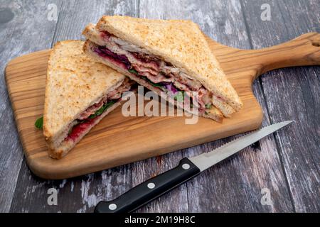 Weihnachtliche Würstchen aus gebratenem truthahn, Speck, Füllung, Rotkohl und roter Johannisbeermarmelade auf einem Holzbrett Stockfoto