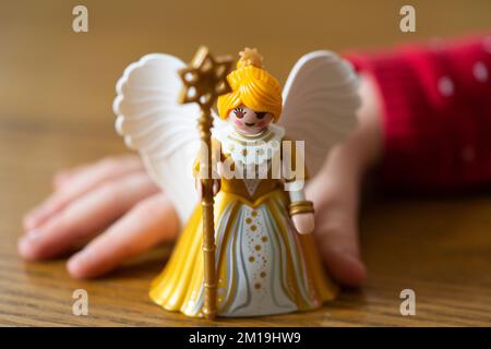 Kleine Kinderhand mit einer Duplo-Figur des Kindergeschenkbringers Christkind (Christkind), Teil der germanischen Tradition am 24.. Dezember Stockfoto