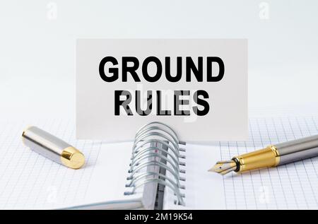 Finanz- und Geschäftskonzept. Auf dem Tisch befinden sich ein Notizbuch, ein Stift und eine Visitenkarte mit der Aufschrift - GRUNDREGELN Stockfoto