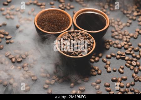 Set aus drei Tassen Kaffeebohnen, gemahlen und getrunken auf schwarzem Hintergrund, Draufsicht auf Kaffee. Stockfoto