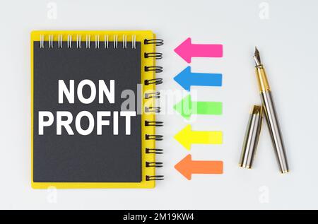Geschäfts- und Finanzkonzept. Auf weißem Hintergrund liegen ein Stift, Pfeile und ein Notizbuch mit der Aufschrift "NON PROFIT" Stockfoto