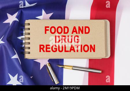 Recht und Ordnung. Vor dem Hintergrund der Flagge der Vereinigten Staaten von Amerika liegt ein Notizbuch mit der Aufschrift "FOOD AND DRUG REGULAT" Stockfoto