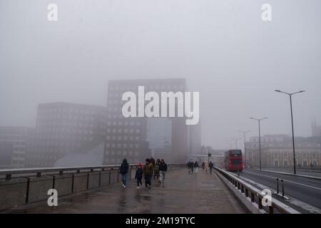 London, Großbritannien. 11.. Dezember 2022 Die Leute gehen auf der London Bridge vorbei am Shard Building, komplett verdeckt von dichtem Nebel. London wachte mit Nebel und eisigen Temperaturen auf, als das arktische Wetter aus Skandinavien, Troll von Trondheim genannt, Großbritannien erreichte. Stockfoto