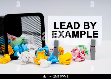 Finanz- und Wirtschaftskonzept. Auf der Tabelle befinden sich Berichtsgrafiken und eine Ideenplatte, in der sie geschrieben ist – MIT GUTEM BEISPIEL VORANGEHEN Stockfoto