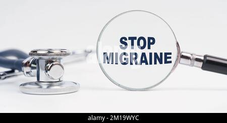 Medizin und Gesundheitskonzept. Auf dem Tisch befindet sich ein Stethoskop, eine Lupe mit der Aufschrift „Stop Migräne“ Stockfoto