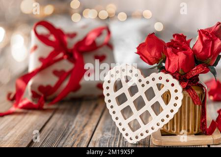 Festlicher Hintergrund zum Valentinstag mit dekorativem Herzen und roten Rosen. Stockfoto