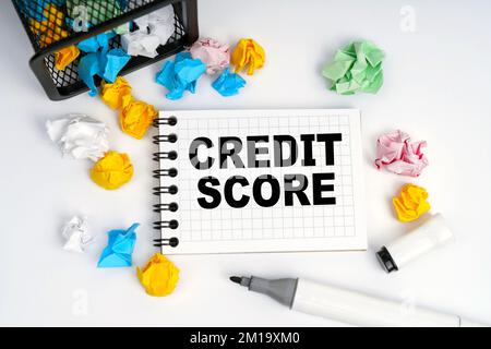 Geschäfts- und Finanzkonzept. Auf dem Tisch befinden sich ein Korb, mehrfarbiges Papier und ein Notizbuch mit der Aufschrift „Credit Score“ Stockfoto