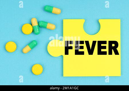 Medizin und Gesundheitskonzept. Auf blauem Hintergrund gibt es Pillen und ein Puzzle mit der Inschrift - FIEBER Stockfoto