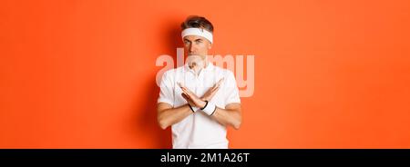 Konzept von Sport, Fitness und Lifestyle. Porträt eines ernsthaft aussehenden männlichen Trainers mit Kreuzzeichen, zu sagen, zu stoppen, etwas zu verbieten und auszudrücken Stockfoto