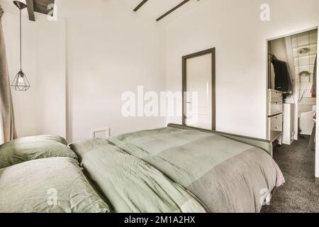 Ein Schlafzimmer mit Bett, Kommode und Spiegel in der Eckwand rechts vom Zimmer ist weiß Stockfoto