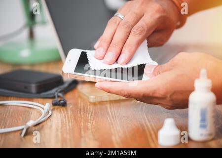 Reinigen Sie das Smartphone mit einem weichen Tuch und Alkohol. COVID-19-Präventionskonzept. Stockfoto