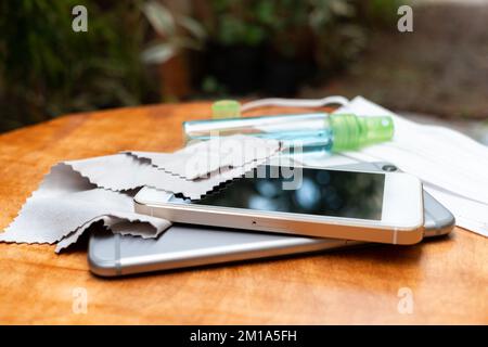 Reinigen Sie das Smartphone mit einem weichen Tuch und Alkohol. COVID-19-Präventionskonzept. Stockfoto