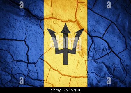 Flagge von Barbados. Barbados-Symbol. Flagge auf dem Hintergrund von trockener, gerissener Erde. Barbados-Flagge mit Dürrekonzept Stockfoto