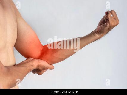 Schmerzen im Ellenbogengelenk eines südostasiatischen jungen Mannes. Konzept von Ellenbogenschmerzen, Verletzungen, Rheuma oder Arthrose. Stockfoto