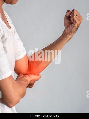 Schmerzen im Ellenbogengelenk eines südostasiatischen jungen Mannes. Konzept von Ellenbogenschmerzen, Verletzungen, Rheuma oder Arthrose. Stockfoto