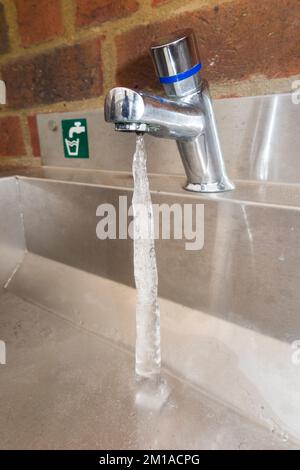 Eissäule, die sich aus einem gefrorenen Tropf aus dem Hahn erstreckt, sodass sich aus dem tropfenden Wasser des undichten Hahns Eis bildet. Hohe Gefahr eines Rohrbruchs durch Frost an einem eiskalten Tag. (132) Stockfoto