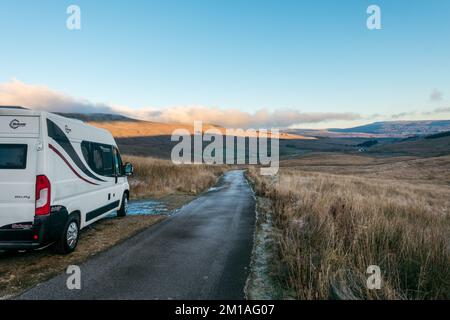 Ein Wohnmobil in einer ruhigen Landstraße in Wensleydale bei Hawes an einem kalten Wintermorgen mit Frost und Eis auf der Straße, Yorkshire UK Stockfoto