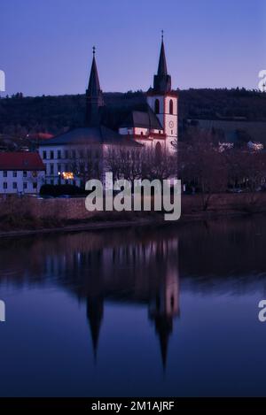 Bingen am Rhein, Deutschland - 10. Januar 2021: Die Basilika St. Martin mit Reflexion am Rhein an einem farbenfrohen Winterabend in Deutschland. Stockfoto
