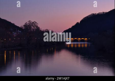 Bingen am Rhein, Deutschland - 10. Januar 2021: Die alte Brücke erleuchtete in einer bunten Winternacht in Bingen mit Reflexionen im Wasser über den Rhein Stockfoto