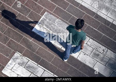 Doha, Katar. 05.. Dezember 2022. Mann, männliche Person überquert eine befestigte Straße an einem Zebrakreuz, wirft einen langen Schatten, aus der Vogelperspektive, von oben. Fußball-Weltmeisterschaft 2022 in Katar ab 20,11. - 18.12.2022 Dollar Kredit: dpa/Alamy Live News Stockfoto