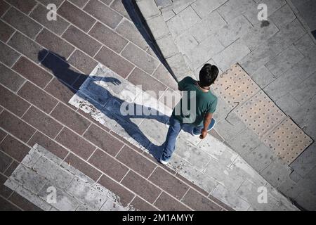 Doha, Katar. 05.. Dezember 2022. Mann, männliche Person überquert eine befestigte Straße an einem Zebrakreuz, wirft einen langen Schatten, aus der Vogelperspektive, von oben. Fußball-Weltmeisterschaft 2022 in Katar ab 20,11. - 18.12.2022? Kredit: dpa/Alamy Live News Stockfoto