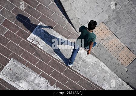 Doha, Katar. 05.. Dezember 2022. Mann, männliche Person überquert eine befestigte Straße an einem Zebrakreuz, wirft einen langen Schatten, aus der Vogelperspektive, von oben. Fußball-Weltmeisterschaft 2022 in Katar ab 20,11. - 18.12.2022 Dollar Kredit: dpa/Alamy Live News Stockfoto