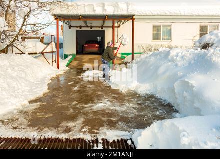 Aktiver älterer Mann Rentnerin reinigt den Hof des Hauses von Schnee Stockfoto